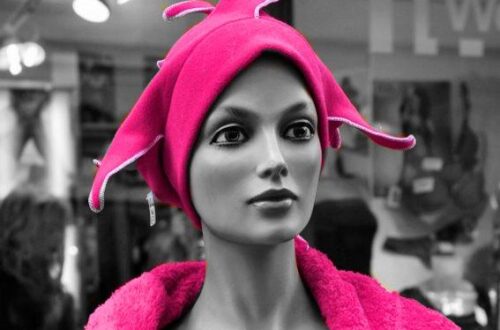 Schwarzweiß-Fotografie einer Schaufensterpuppe mit kräftig pinker Kopfbedeckung und pinkem Oberteil.